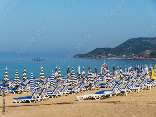 Bild auf Leinwand Beach resort with sunbeds and striped umbrellas by the sea