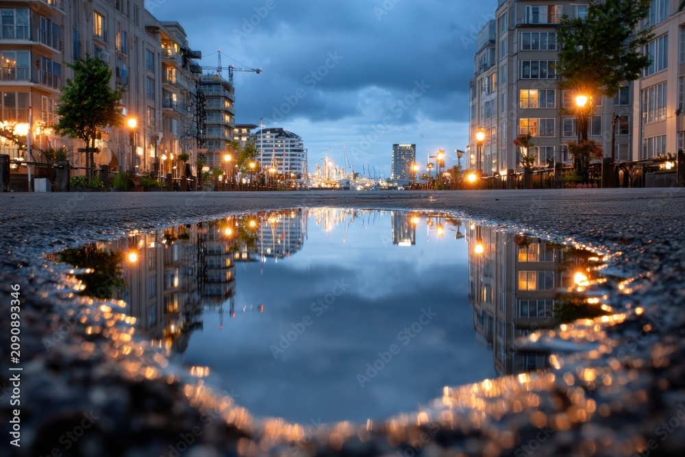 Fototapeta premium Cityscape Reflected in Puddle at Dusk
