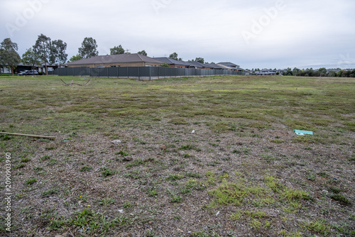 Fotografie Vacant residential land with dry patchy grass beside established homes in Tarneit Melbourne Australia