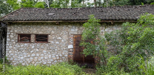 Canvastavla Abandoned stone and brick barn building overtaken by vegetation in a state-owned forest plantation in Guangxi China