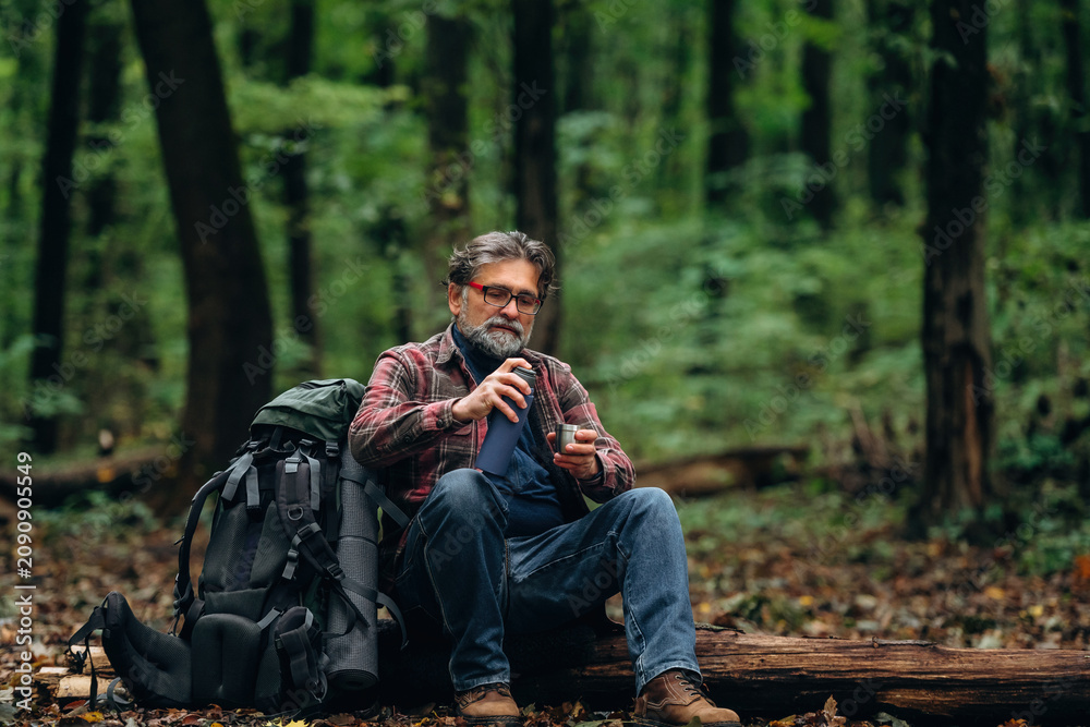 Fototapeta premium Hiking experience, senior man is in the forest at daytime