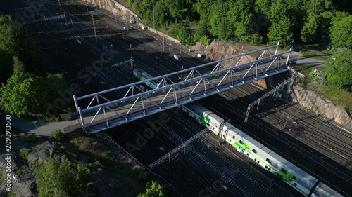 Aerial drone view of Linnunlaulu Bridge by Töölönlahti in Helsinki, Finland, crossing over the railway tracks.