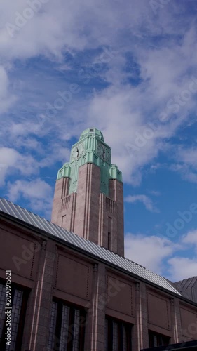 Dramatic clouds moving across the sky above Helsinki city center, with the historic Helsinki Central Railway Station clock tower and urban buildings in the foreground.