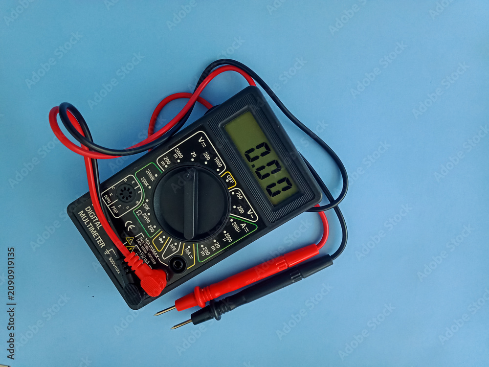 Fotografie Electronic digital multimeter with probes on blue background