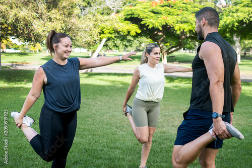 Foto Fitness friends stretching together before an outdoor workout in a park