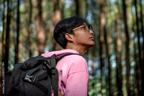 Young Hiker with Backpack Looking Up in a Pine Forest