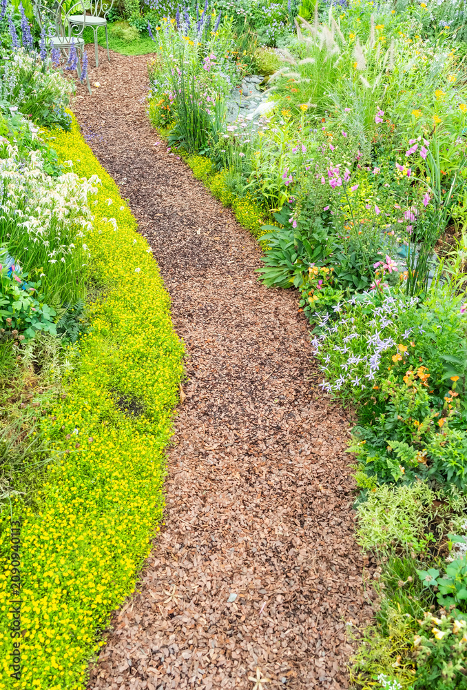 Naklejka premium colorful flowers with rock path leading through a flower garden
