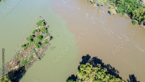 Aerial view of the confluence of the Vaal river and the Orange river south of the town of Douglas, Northern Cape, where brown and green river water merge