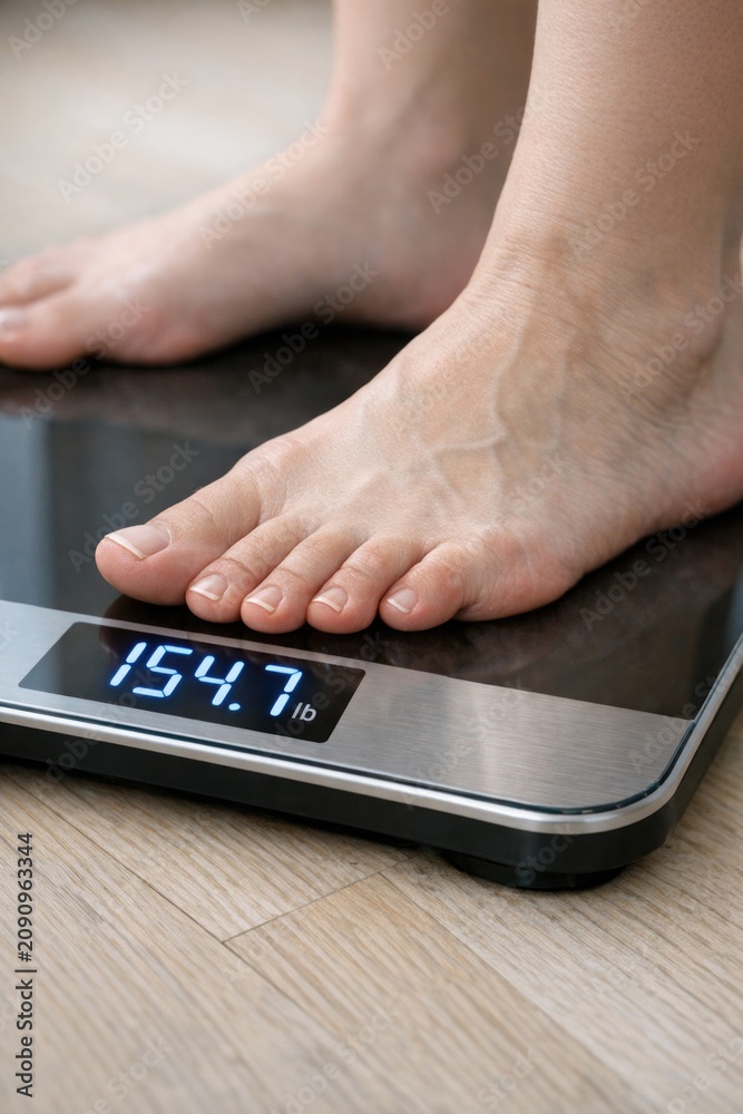 Fototapeta premium A person measures their weight using a standard scale
