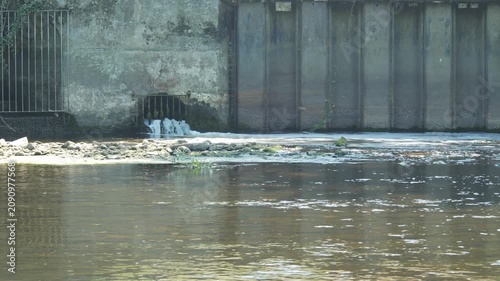 View of water flowing from a wastewater treatment works into a river on a sunny day in the UK