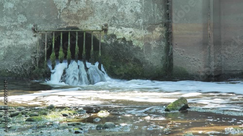 View of water flowing from a wastewater treatment works into a river on a sunny day in the UK