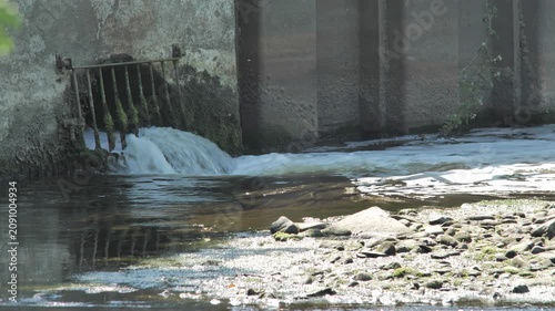 View of water flowing from a wastewater treatment works into a river on a sunny day in the UK