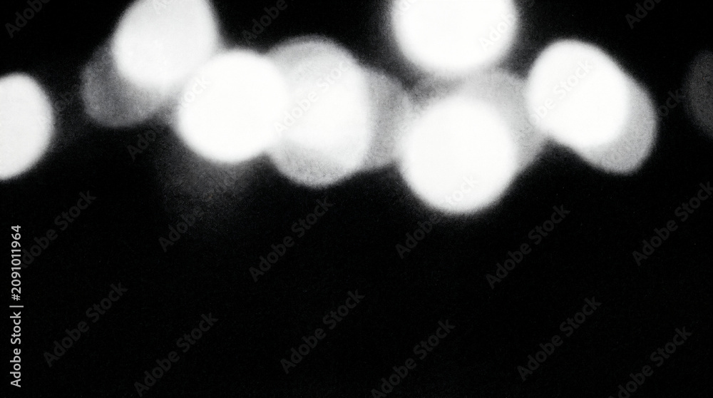 Fototapeta premium Abstract bokeh lights on black background, blurred glowing circles, monochrome defocused night light texture backdrop
