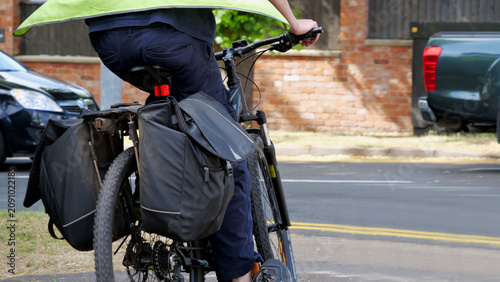 Foto Cyclist with pannier bags riding bicycle on city street, rear view of commuter i