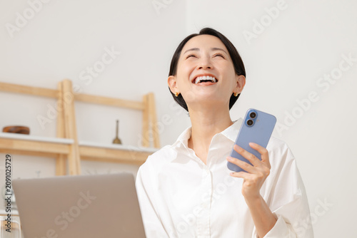 スマホを見てパソコン操作をする女性