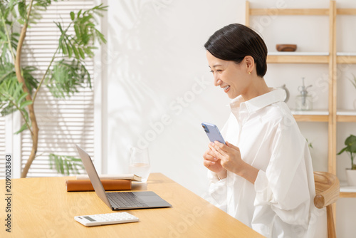 スマホを見てパソコン操作をする女性