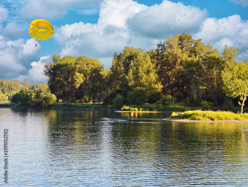 Yellow parachute can be seen in the sky above the water, indicating popular outdoor activities such as parasailing.
