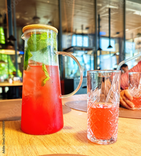 Refreshing drink is a strawberry mojito, served in a large glass jug with a wooden lid.