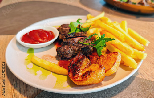 Dish consists of sliced steak, served with chips and ketchup.