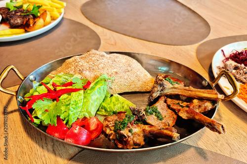 Grilled rack of lamb. The meat is served with a side of fresh salad, tomatoes and flatbread.