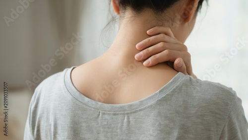Woman touching her neck feeling pain and stiffness from muscle strain at home
