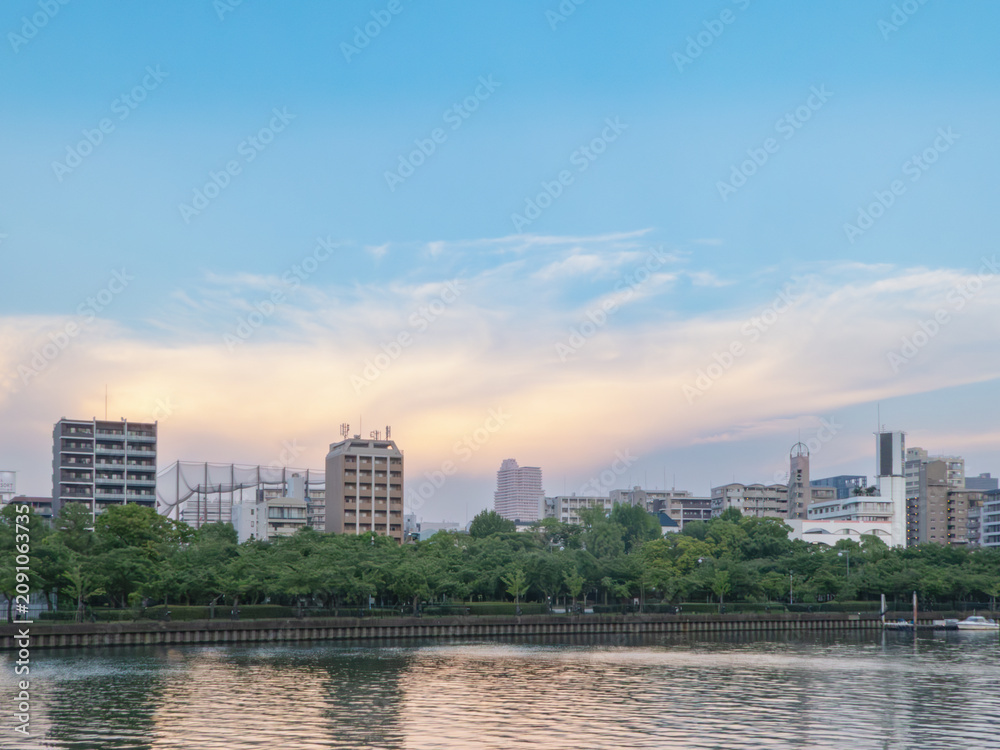 Obraz premium 夕暮れ時の水辺の街並みと広がる夕雲