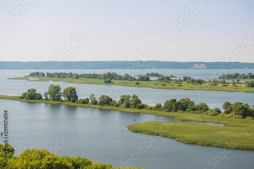 Natural scene with tranquil river meanders through green field and open marsh