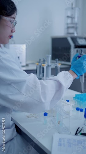 Asian scientist pipetting liquid into test tubes for scientific research in a modern laboratory