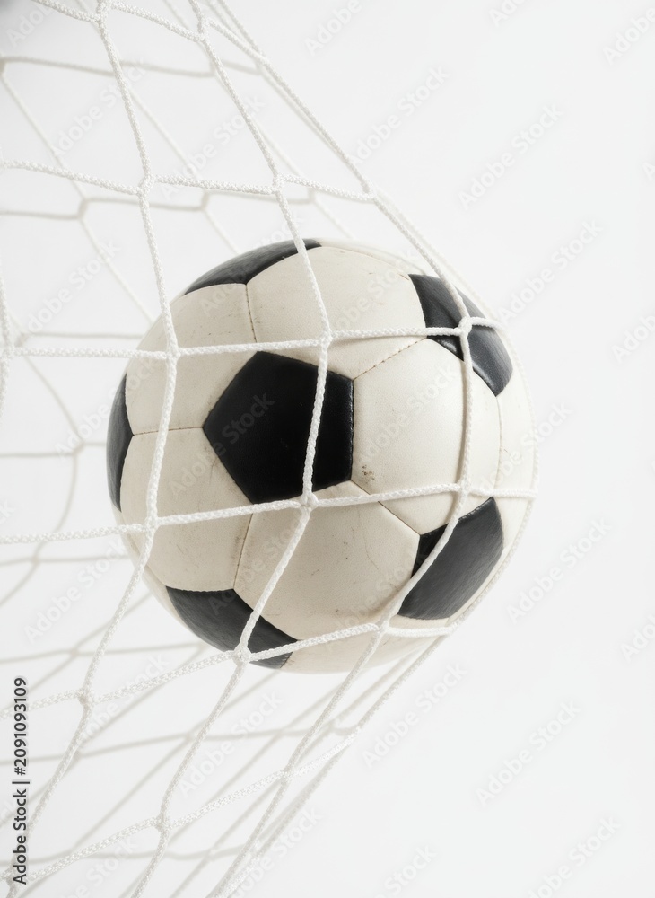 Naklejka premium Close up of a classic soccer ball in the net isolated on white background.