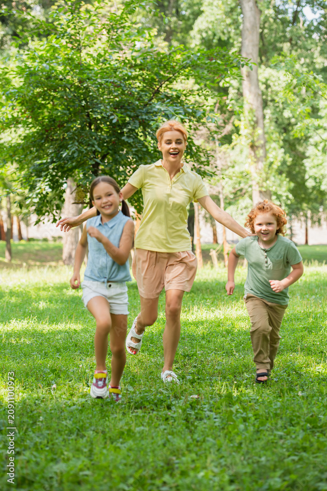 Fototapeta premium Joyful moments at the playground with mother and children in a sunny green setting