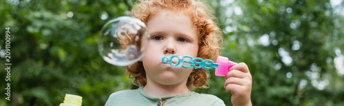 фотографія Joyful moments of a little child blowing bubbles in the park during a sunny afte