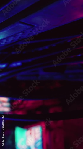 The scene shows a lively nightclub with colorful lights illuminating the space. People enjoy music while moving under bright, flashing colors. The atmosphere is energetic and engaging.