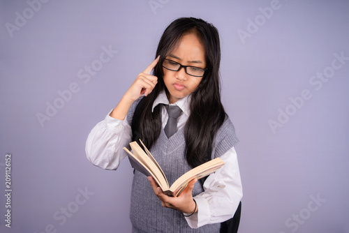 Konstfotografi Serious Asian schoolgirl thinking while reading a book