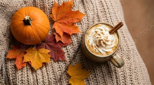 Autumnal still life pumpkin maple leaves and spiced latte on knitted fabric