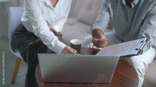 Business colleagues reviewing contract terms and using smartphone calculator for financial analysis in modern office meeting