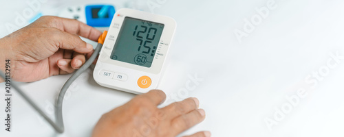 Cuadro en lienzo Close-up of a digital blood pressure monitor displaying a healthy reading while an adult checks cardiovascular health at home