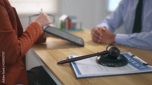 Female lawyer discussing real estate contract with client in law office with judge's gavel on the desk