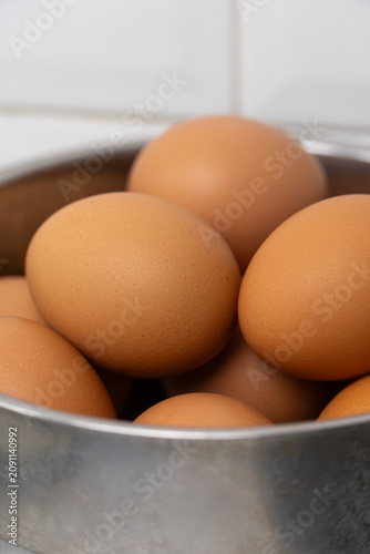Pile of fresh brown eggs in stainless steel container
