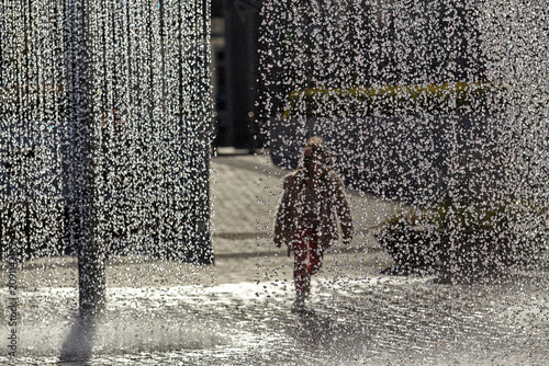 Fotografie Europe heatwave concept with blurred child running through city fountain