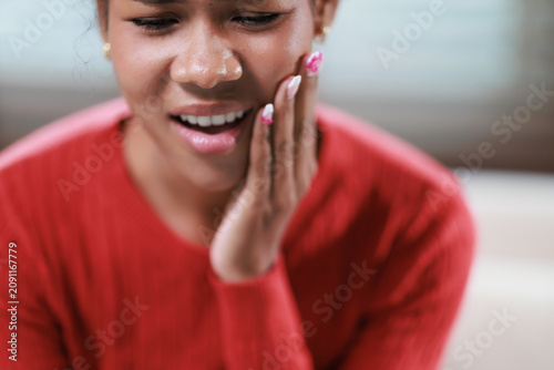 Fotografía Woman experiencing severe toothache, touching her cheek in discomfort, suffering