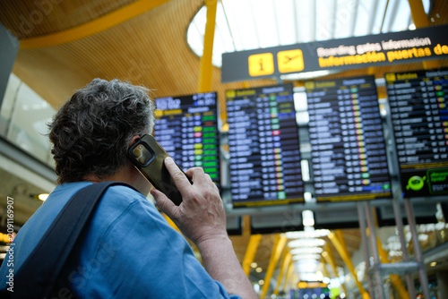 Man calling on phone checking airport flight information