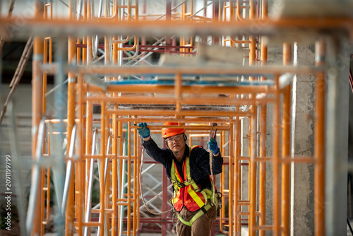 Canvastavla Construction worker safely maneuvering through scaffolding at a job site wearing