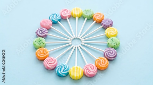 Colorful lollipops arranged on a white Ferris wheel against a light blue background