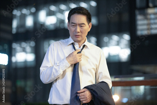 Konstfotografi Stressed businessman loosening tie at night in urban office district