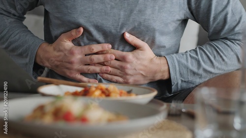 Man suffering from stomach ache holding belly after meal experiencing indigestion and discomfort.