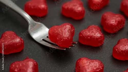 Red Heart Shaped Candies on a Fork Among Other Candies on a Dark Surface