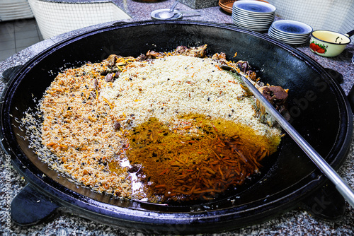 Canvastavla Large traditional kazan filled with Uzbek plov during the final steaming stage in a professional restaurant kitchen