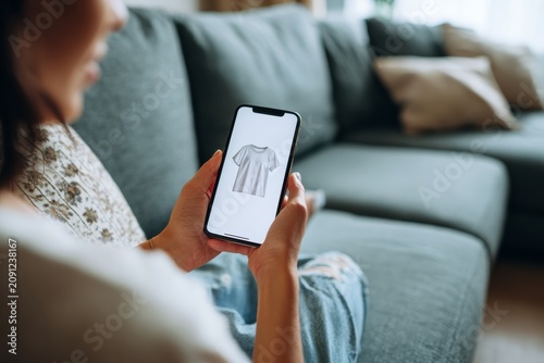 online shopping, EU raising tax on non-EU shipping items, woman sitting a o couch, holding a mobile phone on the screen is a shirt for concept of online shopping, minimal style, 