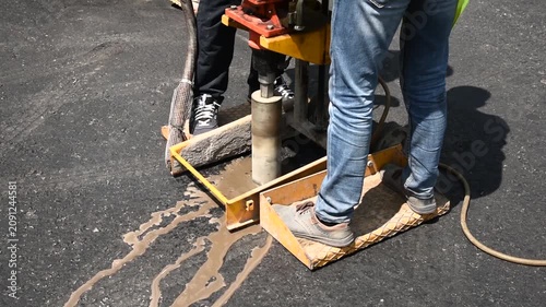 Road worker drilling asphalt core sample for pavement quality inspection