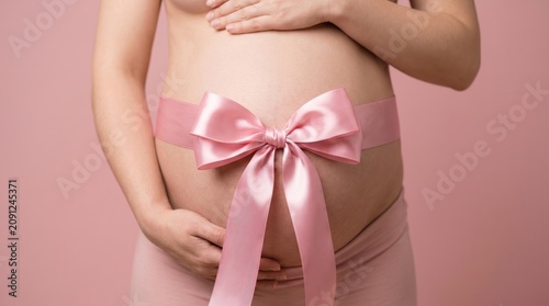A pregnant woman with a pink ribbon bow on her belly. Concept for maternity, motherhood, and celebration, ideal for use in family, health, and wellness contexts. Generative AI